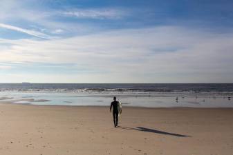 A surfer approaches the Atlantic Ocean at Rockaway’s Beach 90th Street in mid-November, when the water temperature hovered around 59 degrees fahrenheit — and the air temperature only reached the high 40’s.