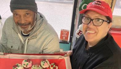 Evette Zayas (right), founder of Cake Burgers in East Harlem, with a regular customer named Ray who won cupcakes in a raffle at the neighborhood store. Photo: Cake Burgers