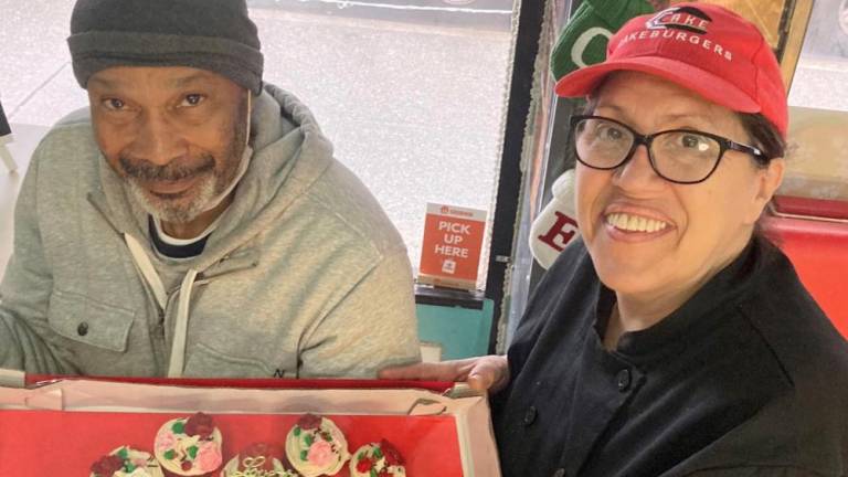 Evette Zayas (right), founder of Cake Burgers in East Harlem, with a regular customer named Ray who won cupcakes in a raffle at the neighborhood store. Photo: Cake Burgers