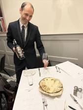 <b>Faridj, the host of Benny John’s Bar &amp; Grill on E. 48th St. off of Fifth Ave., gives a warm welcome and showcases a $95 bottle of kosher wine to our East Side Observer celebrating Passover at the newly opened steakhouse.</b> Photo: M. Brei