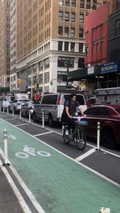 A biker heads the wrong way down a protected bike lane on Eighth Avenue in Chelsea.