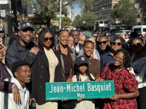Basquiat family members holding up the new street sign on the corner of Great Jones Street and Bowery.