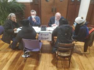 At a recent gathering of New York Justice for Our Neighbors, TJ Mills, the NY-JFON managing attorney (blue sweater) and Rev. Paul Fleck, NY-JFON’s executive director (back right) join in dispensing legal advice to immigrants using a translator (far left) Photo: Stephan Russo