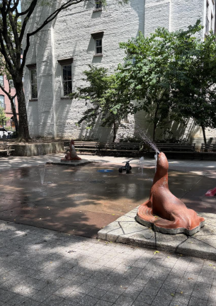 Seal sprinklers spout cooling water at Clement Clarke Moore Park in Chelsea. Citizens were being urged to stay inside as a brutal heat wave hit the city Monday.