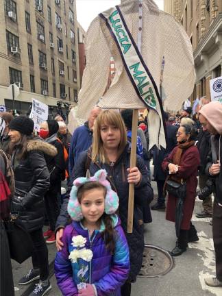 Kimberly Schiller carries a shirtwaist banner with the name of one of the 146 people who died in the Triangle Shirtwaist Factory Fire in 1911 in the biggest fire tragedy in the city’s history. Her daughter Anna Lee carries three white roses. The victims were mostly poor Jewish and Italian immigrants.<b> Photo: Keith J. Kelly</b>