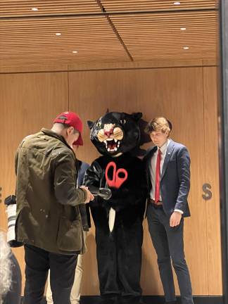The school’s mascot, a panther, posed with students and the ribbon-cutting scissors.