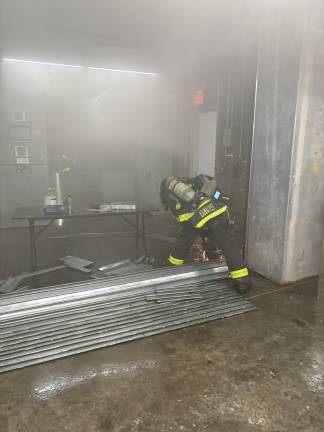 Firefighter cuts through metal gate to access source of fire about a half mile below street level in the Grand Central Madison station.
