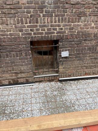 An exposed opening to the building covered up with wood. Residents say openings in basement windows are letting rats in. Photo: Scott Lewis Fischbein