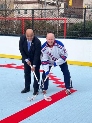 State Assembly Member Eddie Gibbs (left) and New York Rangers alum Brian Mullen (right), posing for hockey-themed photos.