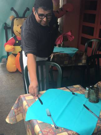 Sebastian Castillo, a server at Maz Mezcal, sets tables for the dinner shift. Maz Mezcal has lost a lot of business since the Second Avenue subway construction began. Photo: Madeleine Thompson
