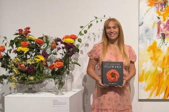 Flower historian and veteran journalist Jill Brooke photographed with her third and newest book, “The Genius of Flowers,” alongside some of Brooke’s blooms.
