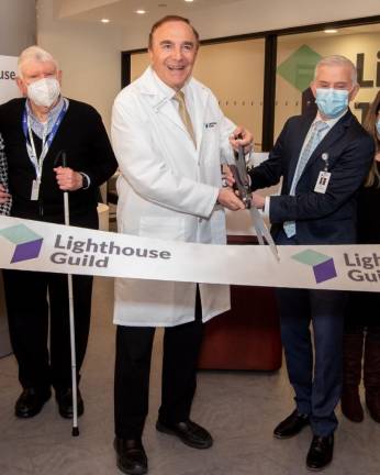 <b>Dr. Calvin Roberts (center) cuts the ribbon at the grand opening of the Lighthouse Guild’s new technology center in 2022 with an assist from COO Paul Misti while LGI client William Graham looks on approvingly.</b> Photo: Courtesy of Lighthouse Guild