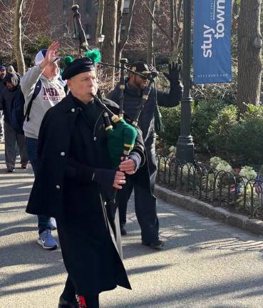 A bag piper leads the opening day parade of the Peter Stuyvesant Little League while former Mets outfielder Endy Chavez (right) and league president Nick McKeon wave to spectators.