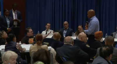 Eric Adams, pictured with mic, having a tense exchange during a “community conversation” at Murray Hill Academy.