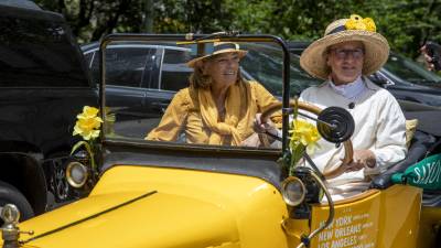 Jeryl Schriever (left) and Susan Nourse (right) pull up to City Hall in a replica of the Golden Flyer, a vehicle of the same make and model that was driven across country in 1916 to fight for the 19th Amendment.