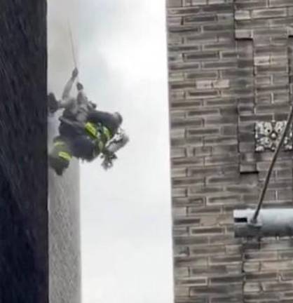 A firefighter rescues a victim from a burning building on St. Nicholas Place in Harlem. Photo: NYPD