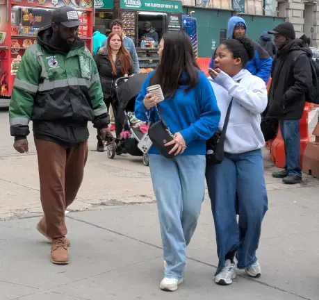 A Battery Park ticket seller offers assistance to female passersby, March 2025.