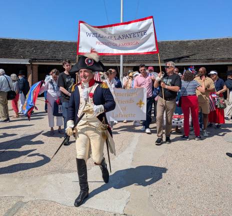 The banner behind the General Lafayette reenactor reads “Welcome Lafayette/Friend of America.”