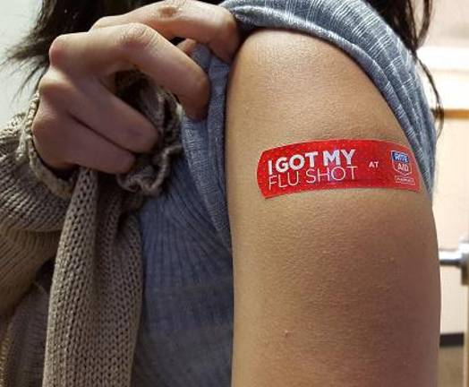 Scenes such as the above, where a young woman shows off her flu-shot sticker, should be commonplace this fall after the FDA in June finally issued recommendations on the new flu vaccine for the 2025-26 flu season.