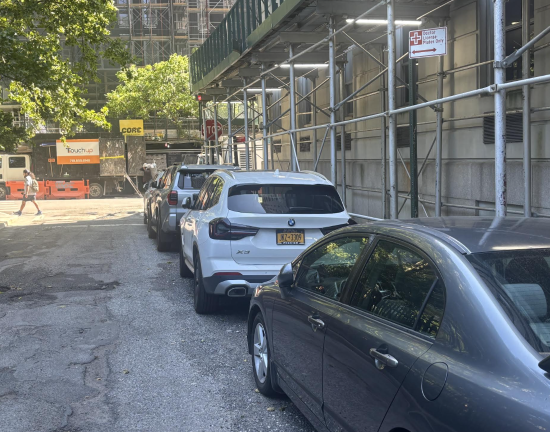 Cars bearing MD plates line E. 16th St. outside the former Beth Israel Hospital which has had no patients since Mount Sinai closed the facility more than three months ago. The DOT has yet to take down the signs designating spots for doctors and ambulances.