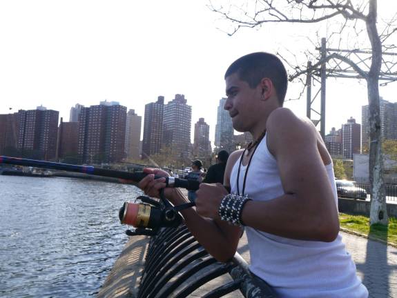 Brandon Torres reels in a bunker fish from the East River. Photo: William Mathis.