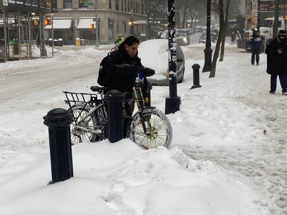 A delivery worker navigates past hefty snowbanks on the Upper West Side.
