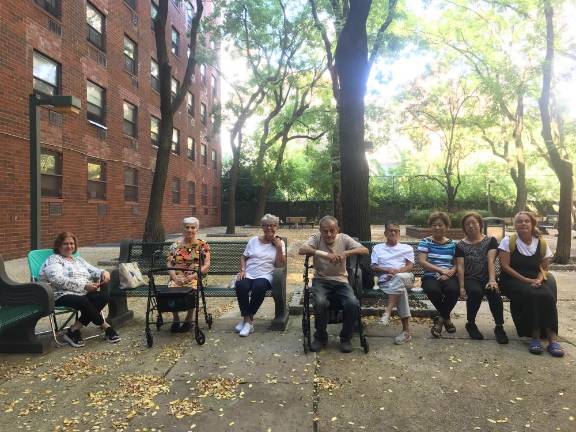 LIRA residents relax in a private courtyard attatched to their housing complex is adjacent to Elizabeth Street Garden. The city wants to take it over and merge it to create a new green space when it builds an affordable housing complex where the garden now stands.