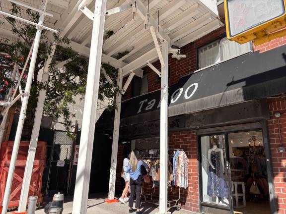 Customers browse outside Taroo, a clothing retailer, beneath a sidewalk shed erected alongside the neighboring tower construction project on First Avenue and East 77th St.