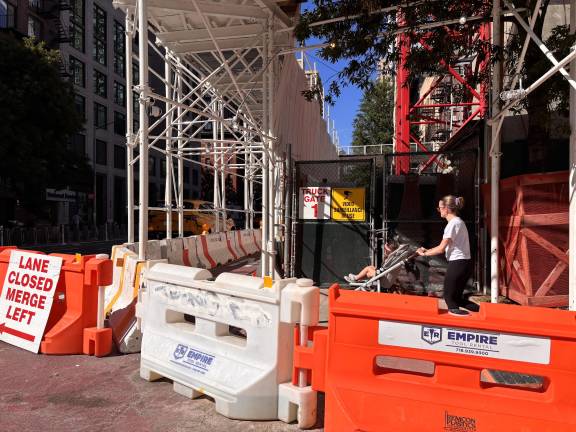 Pedestrians navigate temporary walkways and barriers surrounding the construction site at 1482-1484 First Ave.