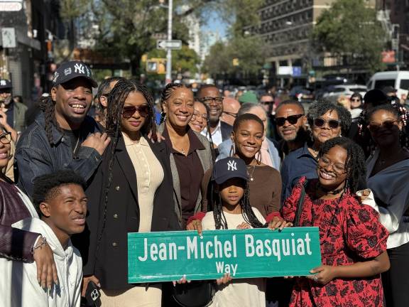 Basquiat family members holding up the new street sign on the corner of Great Jones Street and Bowery.