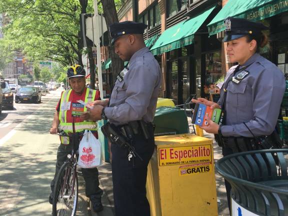 Officers from the 19th Precinct hand out road safety flyers to passers-by at the corner of East 79th Street and First Avenue as part of Vision Zero and a collaboration with Councilman Ben Kallos' office. Photo: Madeleine Thompson