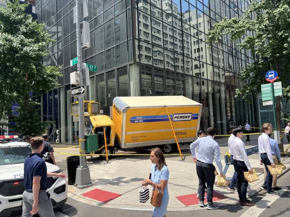 A Penske box truck being temporarily propped up after hitting the awning outside a French luxury furniture store.