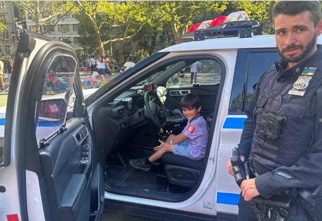 Officer Avinello stands guard as kids get to sit in the driver’s seat on an NYPD cruiser.