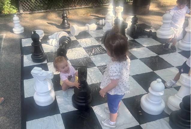 A two-year-old girl strike up a friendship with a 13-month-old on the giant chess board.