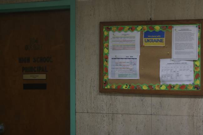 On a bulletin board, a sheet of paper saying “We stand with UKRAINE” is pinned up on the cork.