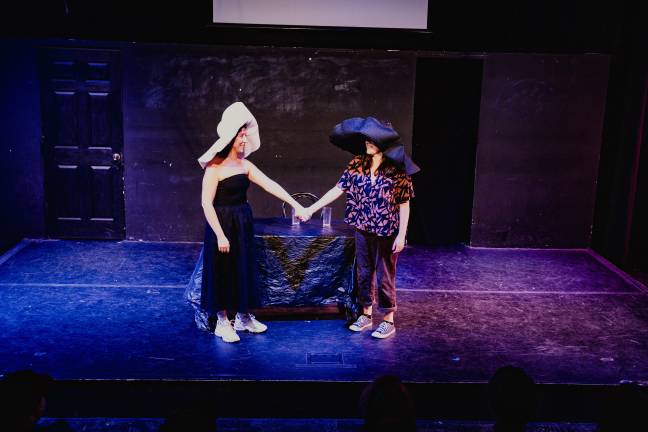 Sarah Franco and Marisa Winckowski hold hands while wearing two large hats.