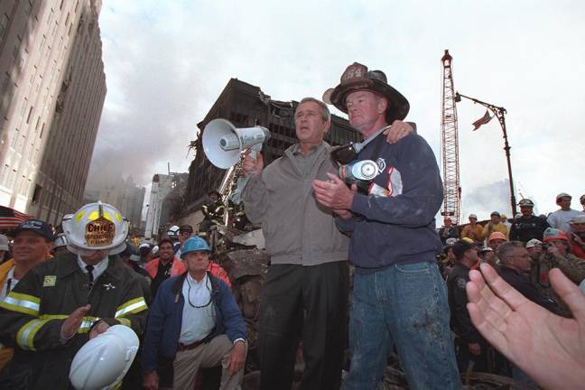 Standing on top of a crumpled fire truck with retired New York City firefighter Bob Beckwith, President George W. Bush rallies firefighters and rescue workers Friday, Sept. 14, 2001, during an impromptu speech at the site of the collapsed World Trade Center towers.