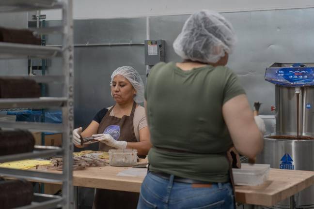 Damarys and Gicela work together on creating separate chocolate molds.