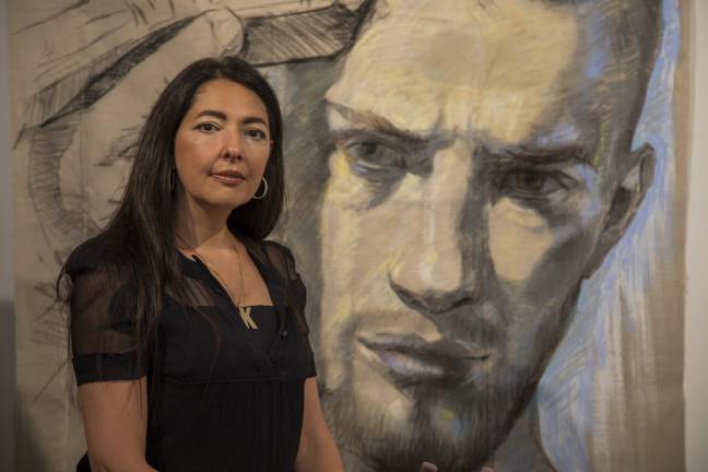 Ukrainian painter Zhenya Gershman stands proudly in front of a portrait she made of a young soldier going off to war in the Russia-Ukrainian war.