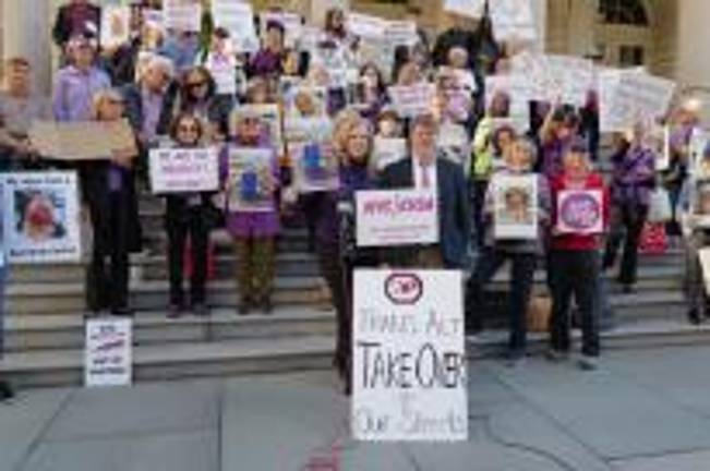 Protestors gathered on the steps of City Hall at a rally sponsored by the E-Vichicle Safety Alliance calling for registration of e-bikes and tougher enforcement. Many victims who were seriously injured by e-bikes said their accidents were never recorded and e-bikers often drove away after the collisions.