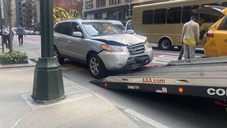 The Hyundai Santa Fe is towed away after a collision with a yellow cab on Third Avenue.