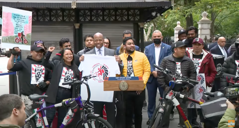 Mayor Eric Adams (center) with delivery workers’ rights activists on Monday. Photo via the Mayor’s Office’s YouTube