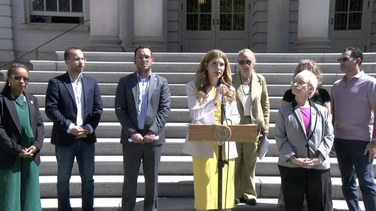 NYC Council Members on the steps of city hall, announcing a Sept. 30 hearing on e-bike safety. From left to right: Council Members Selvena Brooks-Powers, Oswald Feliz, Majority Leader Shaun Abreu, Speaker Julie Menin, Gale Brewer, and Lynn Schulman. Council Members were joined by Jessica Solano, who’s been caring for her sister after she was severely injured by an e-bike while jogging, and Solano’s husband, Brian (right).