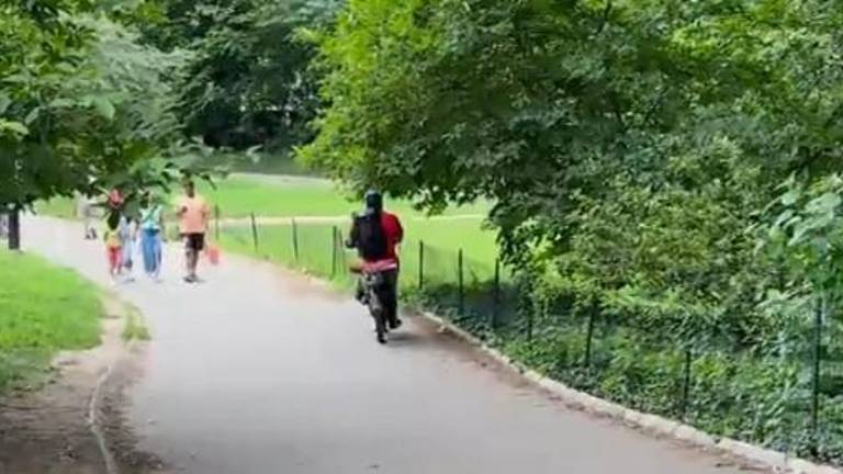 A deliverista, who is riding illegally on a pedestrian walkway in Central Park, bears down on a family walking on the path.